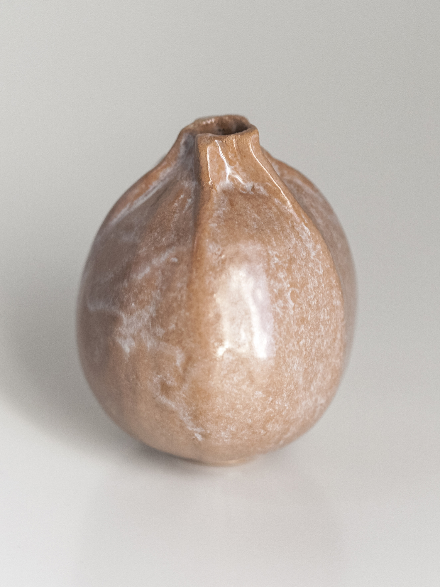 Immagine di zucchina di ceramica di colore neutro su sfondo bianco.