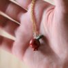 immagine di collana in ottone con ciondolo in ceramica a forma di piccola melagrana rossa