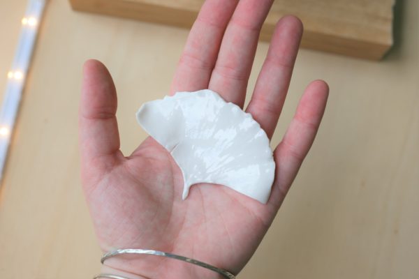 Immagine di spilla Gingko in porcellana bianca su mano di persona