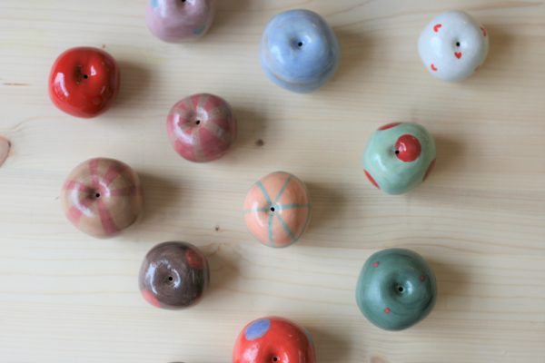 immagine di mele in ceramica colorate realizzate a mano in ceramica su sfondo colore legno chiaro