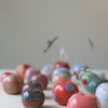 immagine di mele campanine in ceramica realizzate a mano in tanti colori su sfondo legno chiaro