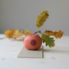 immagine di mela campanina artigianale in ceramica, colori arancione e bordeaux, cariante Milì.