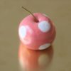 immagine di mela campanina artigianale in ceramica su sfondo ottone, colore rosa acceso e pois bianchi